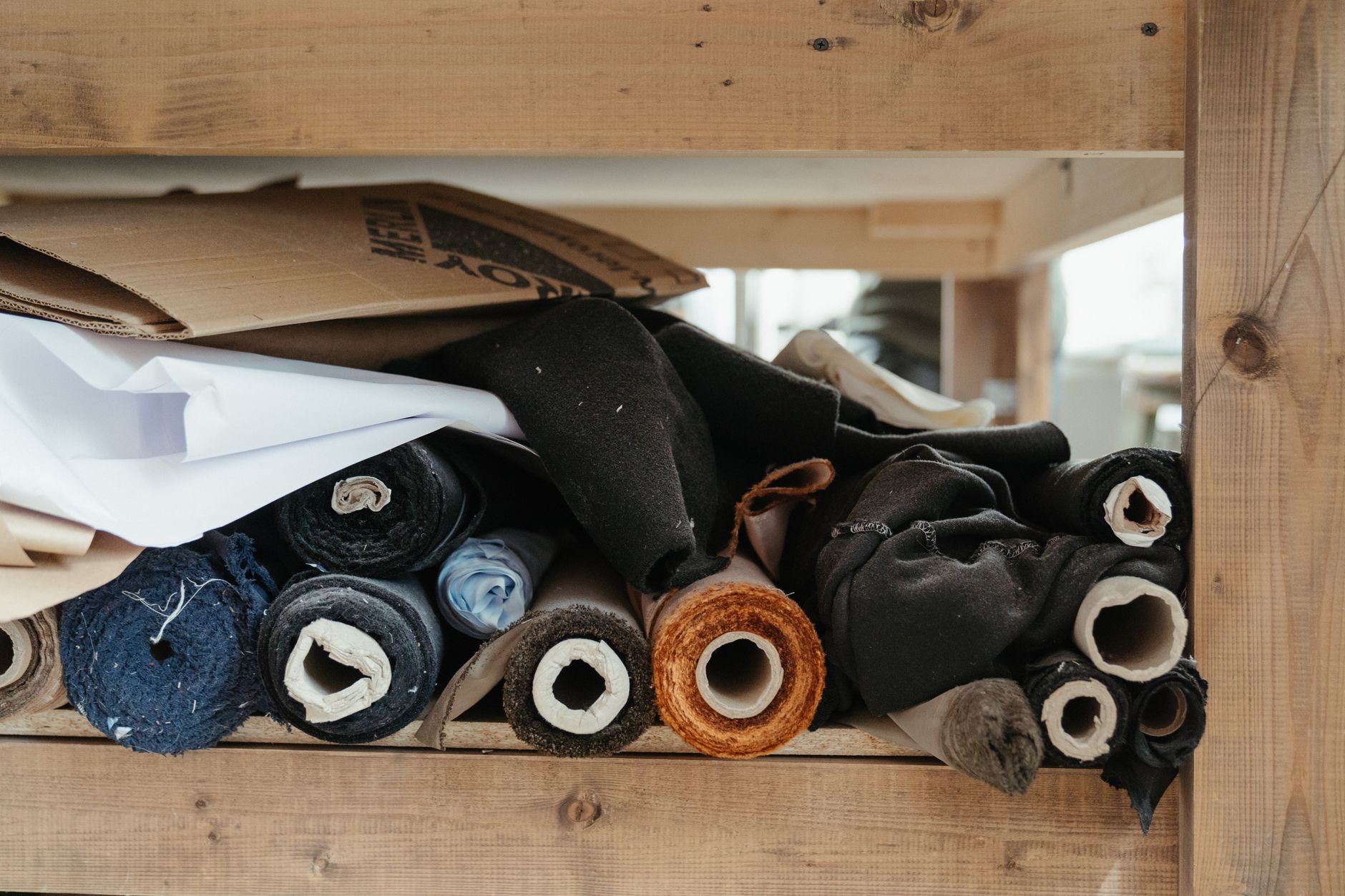 Close-up of diverse fabric rolls neatly arranged in an artisanal workshop setting.